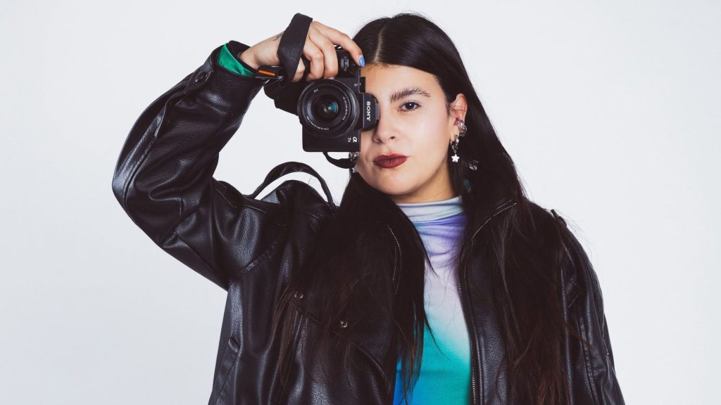 Dolce, fotógrafa de moda chilena, sosteniendo una cámara Sony frente a su rostro. Imagen cedida por la fotógrafa.